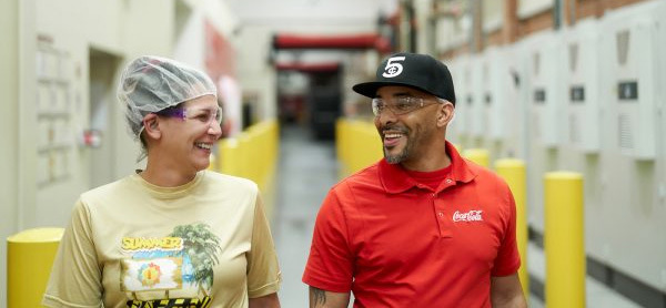 Man and woman smiling walking in hall of manufacturing facility